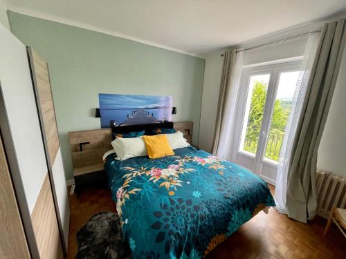 une chambre avec un lit avec une couette bleue et une fenêtre dans l'établissement Maison avec Terrasse Surplombant la Vallée, à Sarlat-la-Canéda