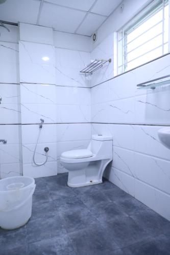 a white bathroom with a toilet and a sink at Western Keys Hotel in Bangalore