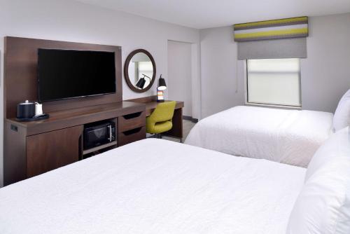 a hotel room with two beds and a flat screen tv at Hampton Inn LaPorte in LaPorte