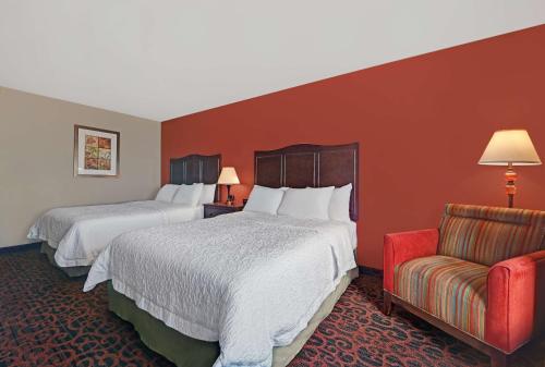 a hotel room with two beds and a chair at Hampton Inn Deming in Deming