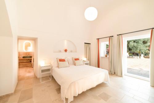 a white bedroom with a bed and a window at Masseria San Nicola Savelletri - B&B in Fasano