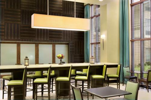 a restaurant with a long bar with green chairs at Hampton Inn & Suites Mahwah in Mahwah