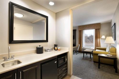 a bathroom with a sink and a mirror and a living room at Hampton Inn & Suites Mahwah in Mahwah