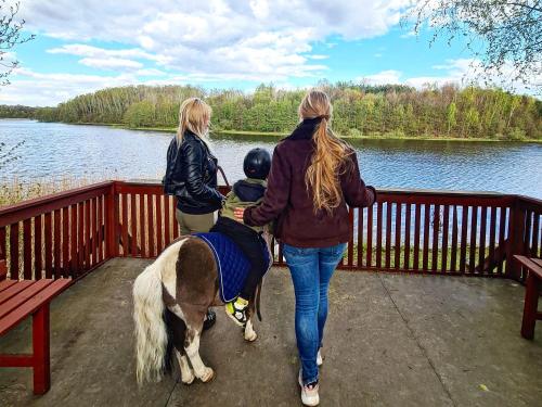 two women and a child walking a pony on a bridge at Agroturystyka Galant in Połęczyno