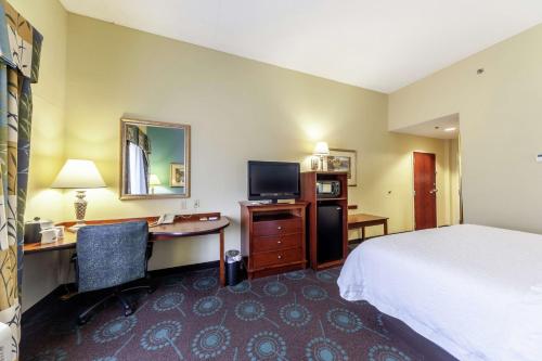 ein Hotelzimmer mit einem Bett, einem Schreibtisch und einem TV in der Unterkunft Hampton Inn Inwood in Inwood