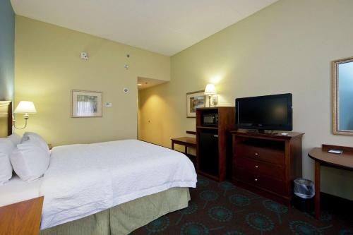 a hotel room with a bed and a flat screen tv at Hampton Inn Inwood in Inwood