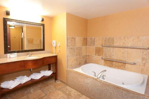 a bathroom with a tub and a sink and a mirror at Hampton Inn & Suites McComb in McComb