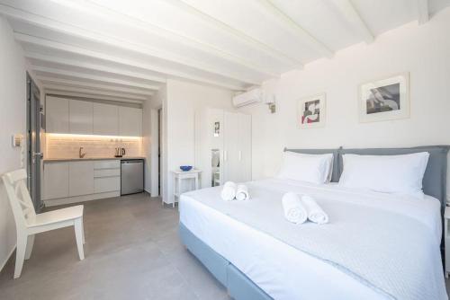 a white bedroom with a large bed and a kitchen at Villa Tholos -Athens Riviera in Kalívia Thorikoú