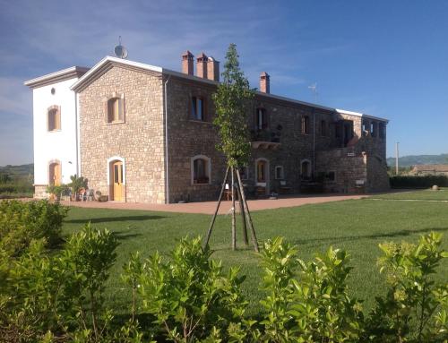 a large brick house with a tree in front of it at Masseria Fontana dei Fieri in Pietrelcina