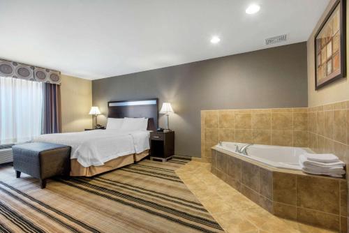 a hotel room with a bed and a bath tub at Hampton Inn Meadville in Meadville