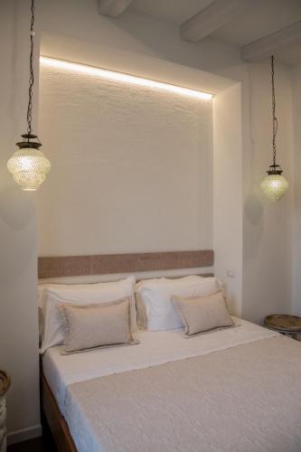 a bedroom with a white bed with two lights at Amelia Apts & Rooms in Alghero
