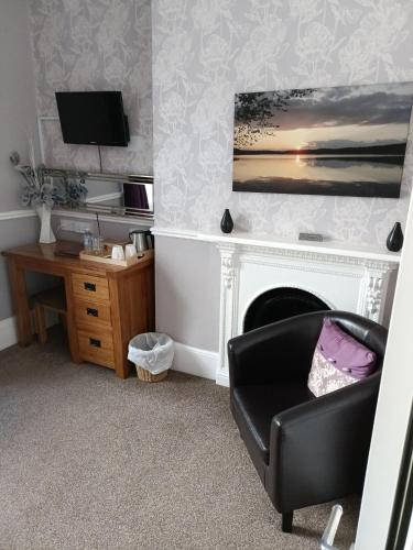 a living room with a fireplace and a chair at Lawnswood Guest House in Torquay