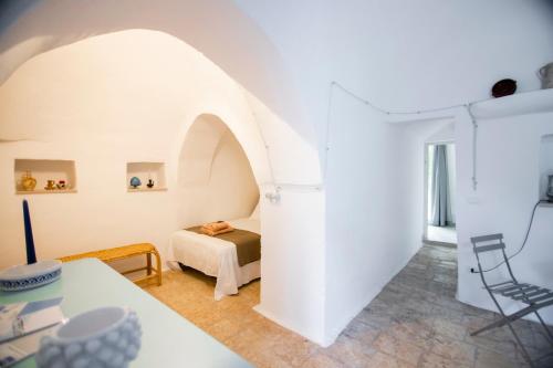 Cette chambre blanche comprend un lit et une table. dans l'établissement Trullo Porta Celeste, à San Michele Salentino