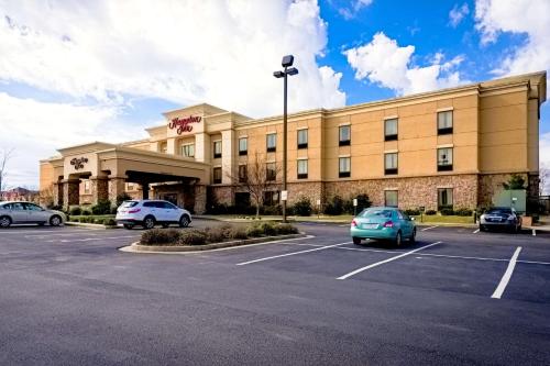 a large building with cars parked in a parking lot at Hampton Inn Montgomery-South-Airport in Hope Hull