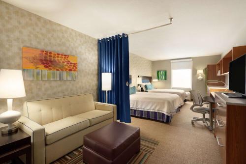 Home2 Suites by Hilton Florida City في مدينة فلوريدا: غرفه فندقيه بسرير واريكه