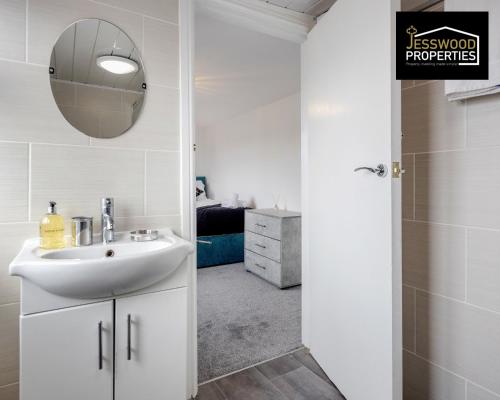 a white bathroom with a sink and a mirror at 6 Bedroom Contractor House at Jesswood Properties Short Lets With Parking,Wifi & Pool Table in Luton