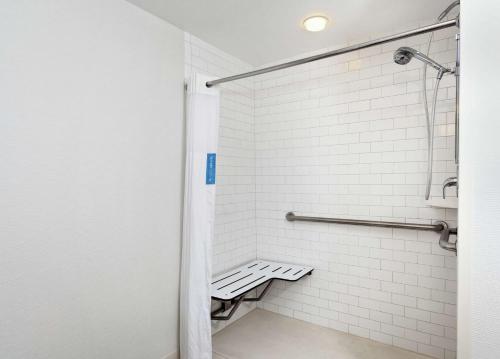a white tiled shower with a bench in a bathroom at Hampton Inn Melbourne in Melbourne