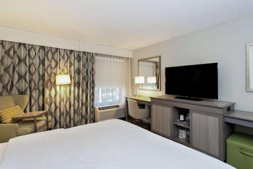 a hotel room with a bed and a flat screen tv at Hampton Inn Melbourne in Melbourne