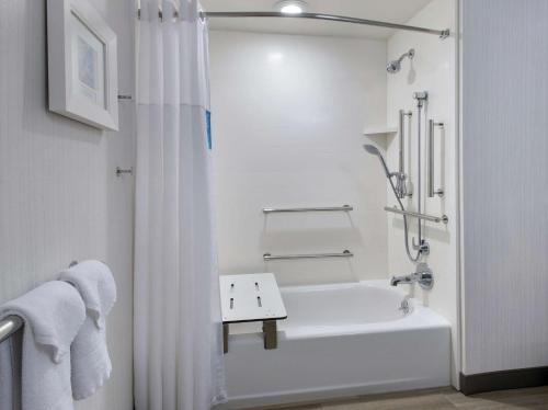 Hampton Inn Middletown في ميدلتاون: حمام أبيض مع حوض استحمام ودش