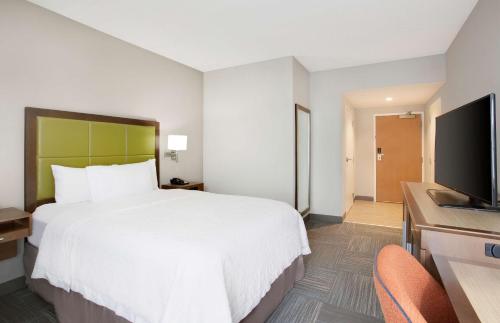 a hotel room with a bed and a flat screen tv at Hampton Inn Middletown in Middletown