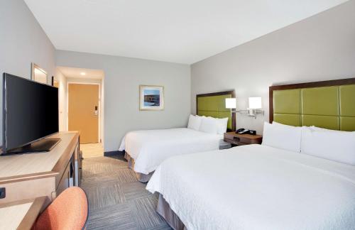 a hotel room with two beds and a flat screen tv at Hampton Inn Middletown in Middletown