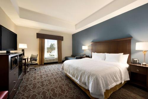 a hotel room with a bed and a flat screen tv at Hampton Inn West Monroe in West Monroe