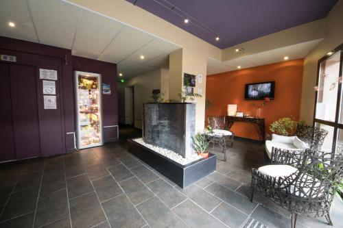 a lobby with a fireplace and tables and chairs at L'HÔTEL de CHARTRES in Chartres