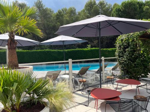 un patio con sillas y sombrillas junto a una piscina en ibis Nîmes Ouest - A9 en Nimes