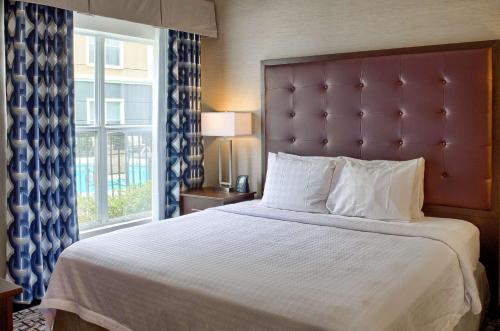 Homewood Suites by Hilton Mobile في موبايل: غرفة نوم بسرير كبير مع نافذة كبيرة