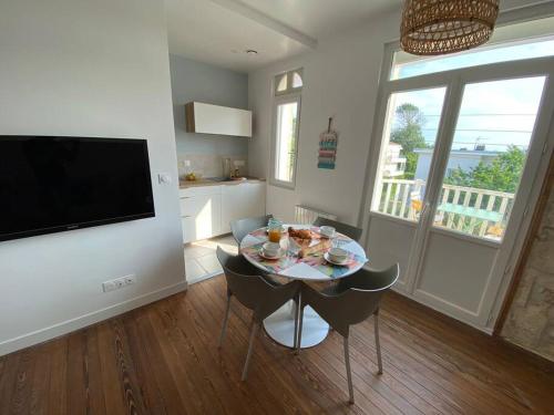 a dining room with a table and chairs and a television at Appartement, Royan. Proche plage. in Royan