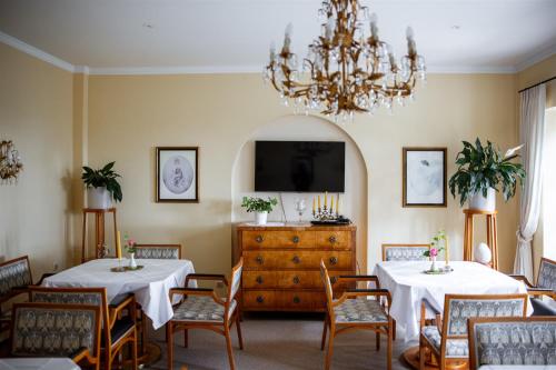 a dining room with two tables and a tv at Kurhaus Dr. Petershofer in Wolfsegg am Hausruck