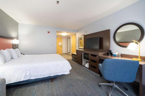 a hotel room with a bed and a desk and a tv at Hampton Inn & Suites Modesto - Salida in Modesto