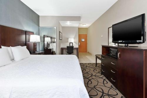 a hotel room with a bed and a flat screen tv at Hampton Inn Monroe in Monroe
