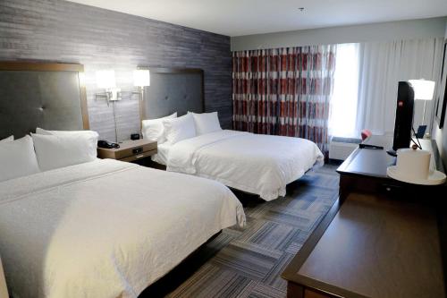 a hotel room with two beds and a television at Hampton Inn Muskogee in Muskogee