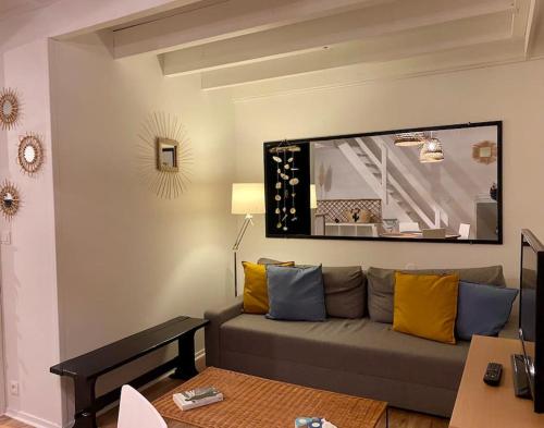 a living room with a couch with yellow and blue pillows at - Appartement Cauris - in Vieux-Boucau-les-Bains