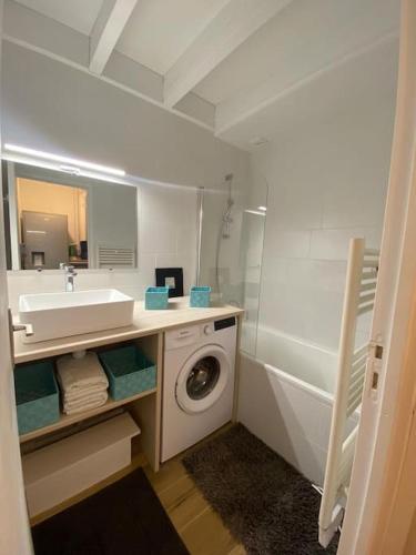 une salle de bain avec un lavabo et une machine à laver dans l'établissement - Appartement Cauris -, à Vieux-Boucau-les-Bains