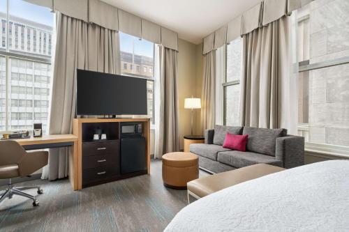 a hotel room with a bed and a couch and a television at Hampton Inn Downtown / French Quarter Area in New Orleans