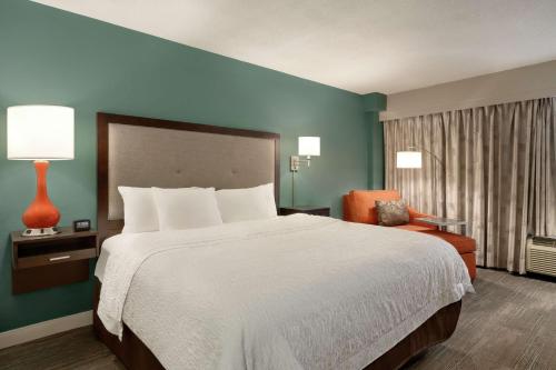 a hotel room with a large bed and a chair at Hampton Inn New Orleans/St.Charles Ave in New Orleans