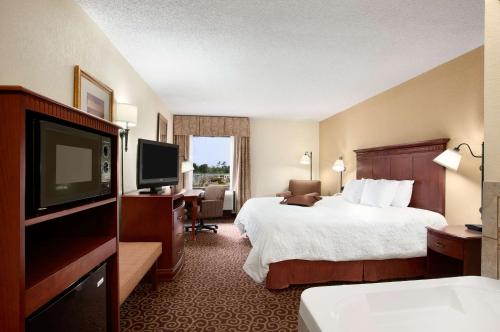 a hotel room with a bed and a flat screen tv at Hampton Inn Slidell in Slidell