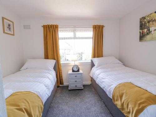two twin beds in a room with a window at 22 Turnberry Road in Girvan