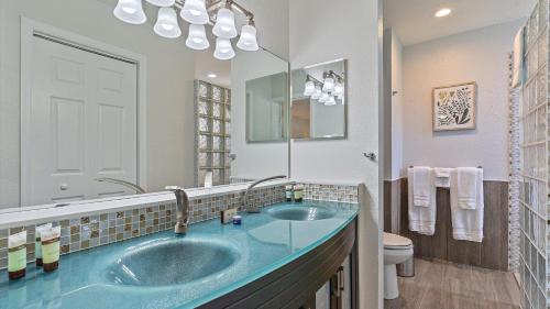 La salle de bains est pourvue d'un lavabo bleu et d'un miroir. dans l'établissement Paradise Palace, à Sarasota