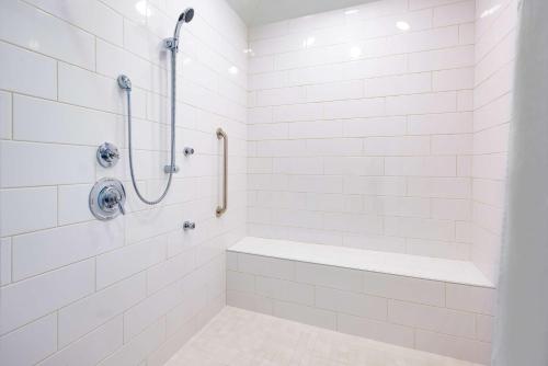 W wyłożonej białymi kafelkami łazience znajduje się prysznic i wanna. w obiekcie Hampton Inn Mount Airy w mieście Mount Airy