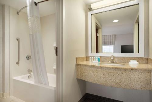 Hampton Inn & Suites Middletown في ميدلتاون: حمام مع حوض ومرآة وحوض استحمام
