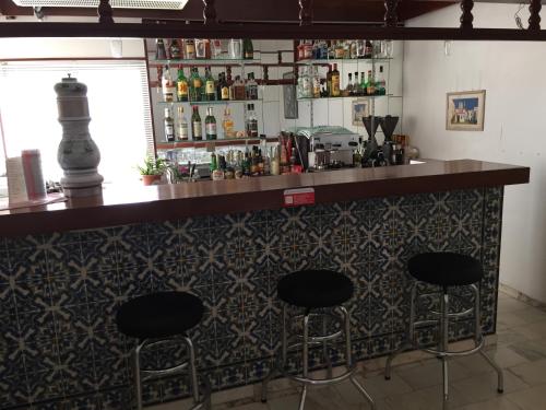 a bar with three stools in a room with a counter at Hotel Albergaria Dom Manuel in Porches