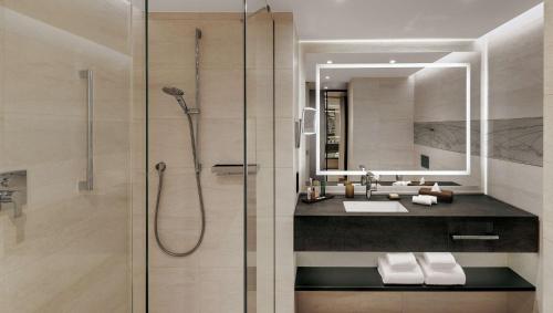 a bathroom with a shower and a sink and a mirror at Hilton Munich Airport in Oberding