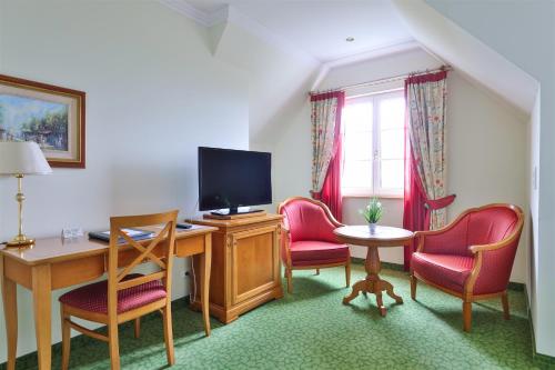 a room with a desk and chairs and a television at Kurhaus Dr. Petershofer in Wolfsegg am Hausruck