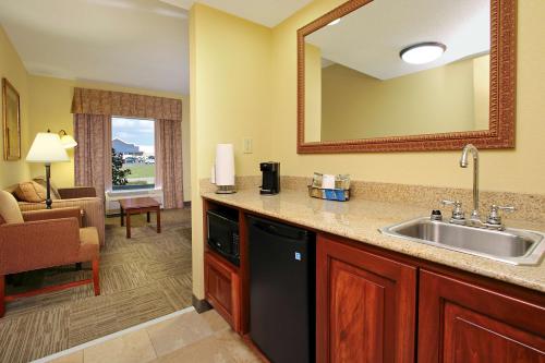a kitchen with a sink and a living room at Hampton Inn & Suites Madisonville in Madisonville