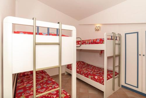 a room with two bunk beds with red sheets at trilocale con piscina in Arzachena