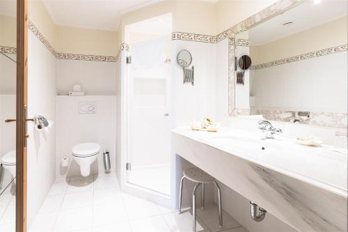 a white bathroom with a sink and a toilet at Kurhaus Dr. Petershofer in Wolfsegg am Hausruck