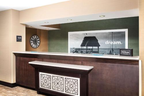 a hotel reception desk with a clock on the wall at Hampton Inn Myrtle Beach West in Myrtle Beach